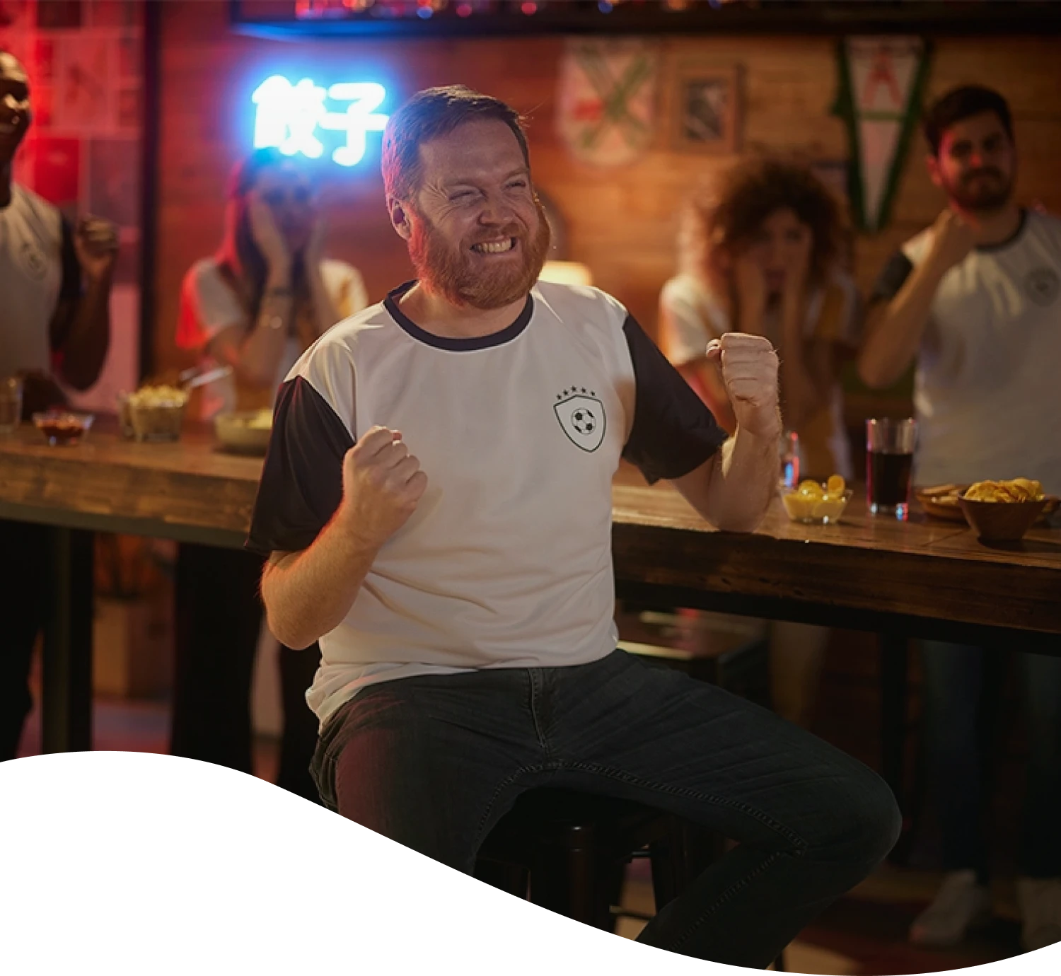 Hombre con remera de futbol festejando en un bar