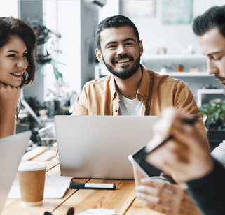 Two men and a woman around a table working and smiling during a meeting.